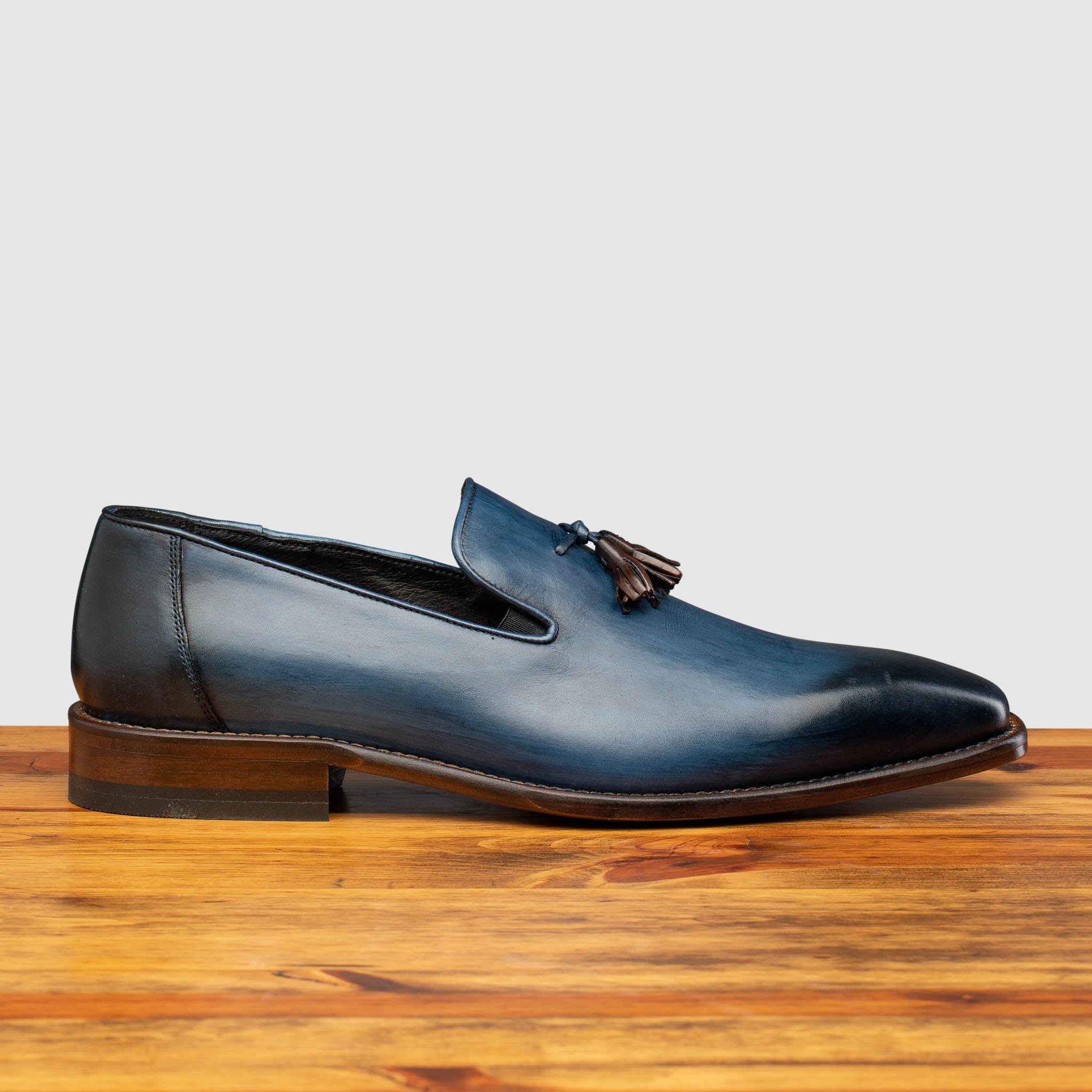 Side profile of Z993 Calzoleria Toscana Ocean Blue David Tassel Slip-On on top of a wooden table